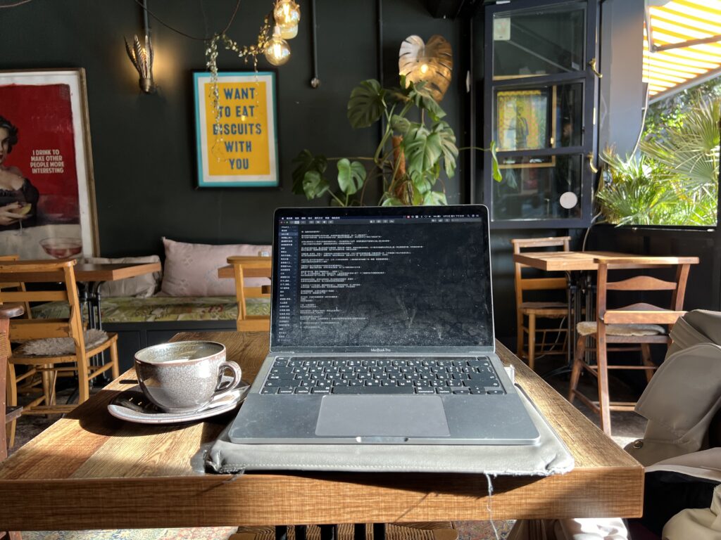 A laptop and a cup of coffee on a cafe table.